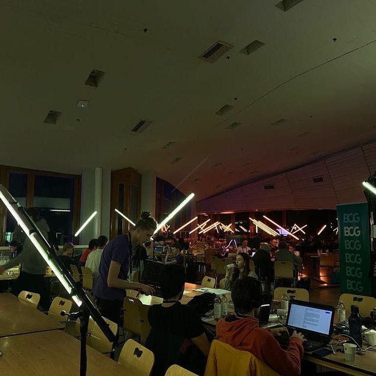 Valokuva Junction-tapahtumasta. Sali, jossa on ihmisiä työskentelemässä tietokoneilla pitkien pöytien ääressä.